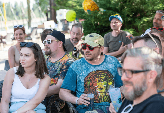 A group of people enjoying an outdoor gathering, wearing sunglasses and casual summer attire.