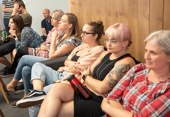 Attentive audience members, sitting with arms crossed, listening intently.